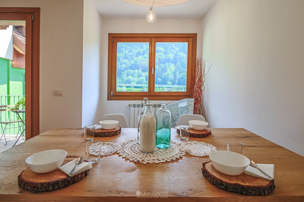 vista sulle montagne e  tavolo in legno apparecchiato con rondelle di legno come sottopiatto, allestimento a Camporosso Tarvisio per appartamento in vendita 